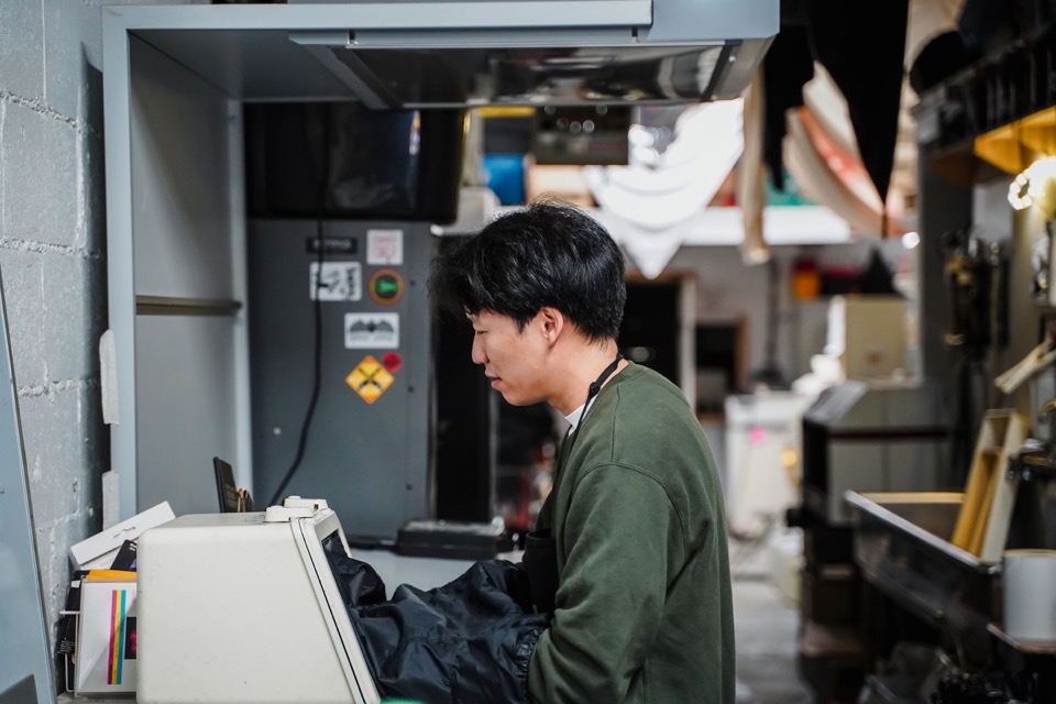 Technician operating equipment in a clean industrial laboratory environment.
